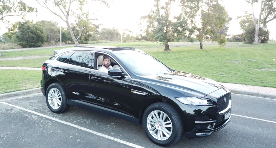 Daniel Byrne in a parked $150,000 Jaguar.