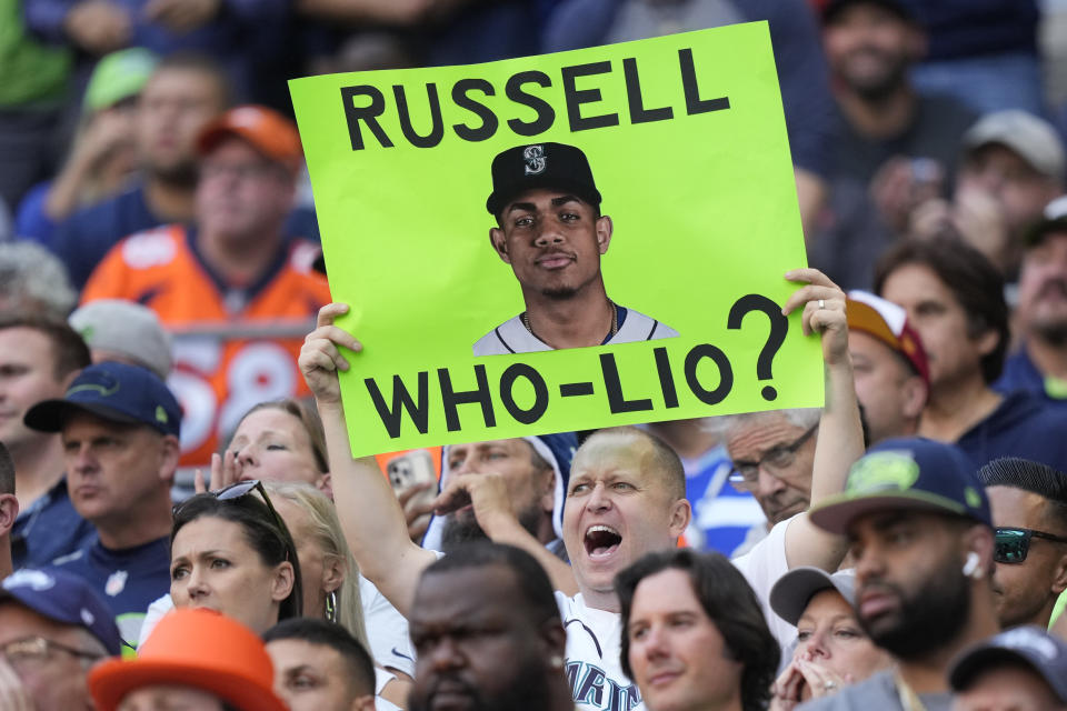 A fan holds up a sign with a photo of Seattle Mariners MLB baseball outfielder Julio Rodriguez that reads "Russell Who-Lio?" in reference to the status in Seattle of former Seattle Seahawks quarterback Russell Wilson, who now plays for the Denver Broncos, during the first half of an NFL football game between the Seahawks and Broncos, Monday, Sept. 12, 2022, in Seattle. (AP Photo/Stephen Brashear)