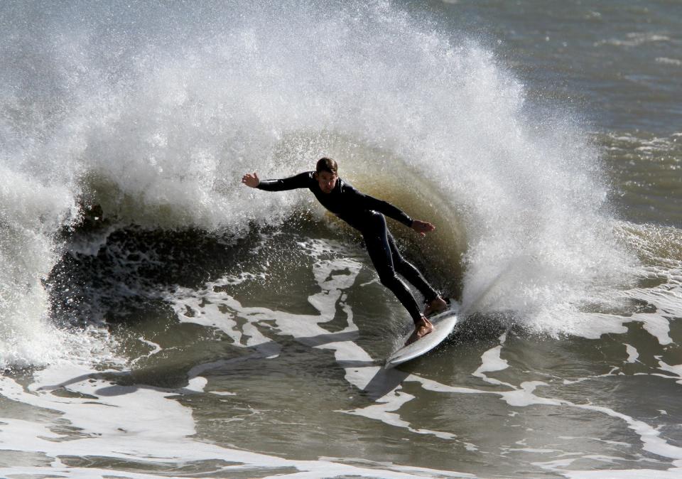 A surfer catches a wave at the southern end of Holgate Friday, October 12, 2018.