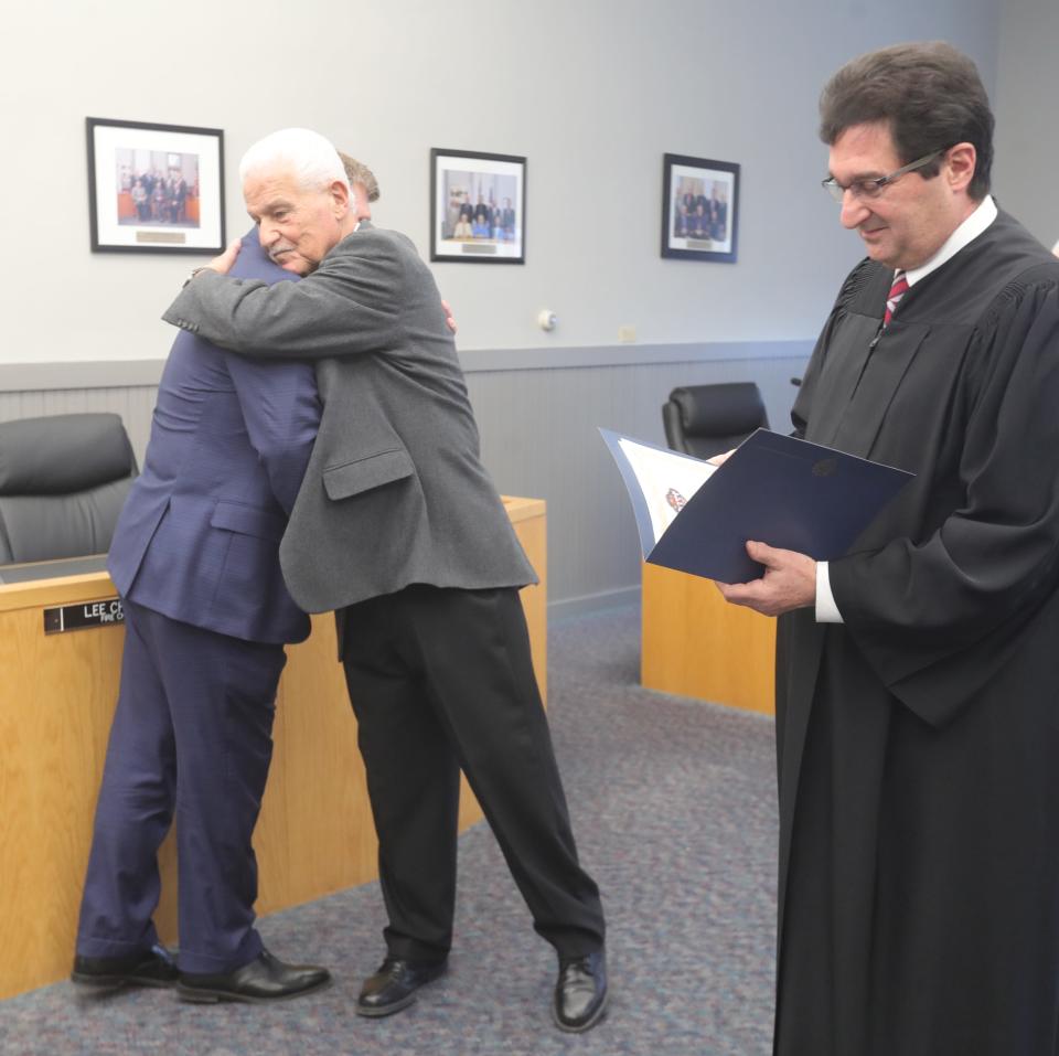 Former Mayor James Armstrong, left, hugs new Mayor Allen Mavrides, during an oath of office ceremony with Ninth District Court of Appeals Judge Tom Teodosio on Jan. 21 in Munroe Falls.