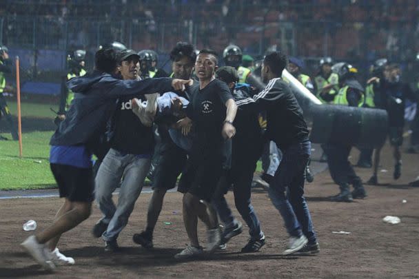 PHOTO: Supporters evacuate a man hit by tear gas fired by police during the riot after the league BRI Liga 1 football match between Arema and Persebaya in Indonesia, on Oct. 2, 2022, in this photo taken by Antara Foto. (Antara Foto/via Reuters)