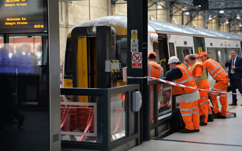 Railway staff at London's Kings Cross station look at a train from Royston which appeared to have hit the buffers - Credit: John Stillwell/PA