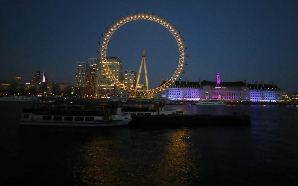 The London Eye is illuminated in yellow to signify a "beacon of remembrance" in London, Tuesday, March 23, 2021. One year since Prime Minister Boris Johnson announced UK-wide lockdown to slow the fast-spreading coronavirus, a national day of reflection is being organized to remember the people who died after contracting COVID-19. The U.K. has registered more than 126,000 virus-related deaths, the highest pandemic death toll in Europe and the fifth-highest worldwide.(AP Photo/Frank Augstein)