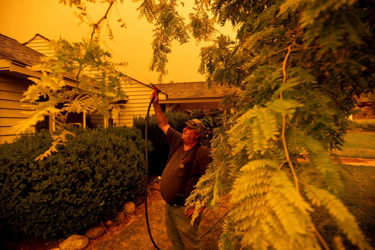 Jerry Whipple wets down his roof as the Dixie Fire approaches the Greenville community in Plumas County, Calif. on Friday, July 23, 2021.