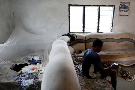 Informal gold miner Yaw Ngoha sits on a sofa in the living room of his home in Bawdie