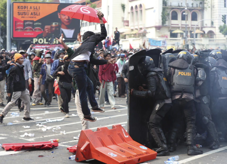 A protester tries to hurl a brick towards police trying block protesters from advancing towards the Presidential Palace during a rally in Jakarta, Indonesia, Thursday, Oct. 8, 2020. Thousands of enraged students and workers staged rallies across Indonesia on Thursday in opposition to a new law they say will cripple labor rights and harm the environment. (AP Photo/Achmad Ibrahim)