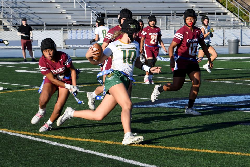 Royal High quarterback Morgan Arrasmith runs around a wall of Oxnard defenders during the Highlanders' 14-0 win in the title game of the Ventura County Girls Flag Football Championship at Camarillo High on Oct. 28.