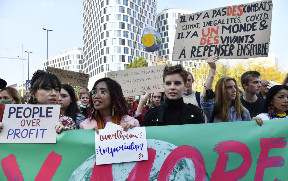 Belgian climate activist Anuna De Wever, center, participates in a climate march in Brussels, Sunday, Oct. 10, 2021. Some 80 organizations are joining in a climate march through Brussels to demand change and push politicians to effective action in Glasgow later this month. Sign at right reads in French, There are no fights; climate, inequality, COVID. There is a world of living to rethink together. (AP Photo/Geert Vanden Wijngaert)