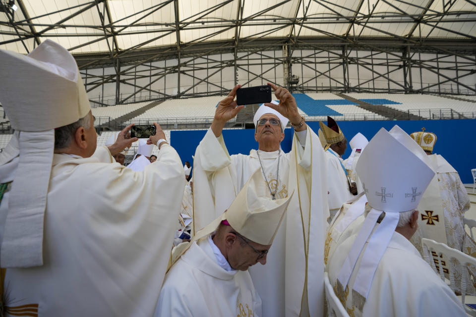 Priests take photos as they wait for the arrival of Pope Francis at the "Velodrome Stadium", in Marseille, France, to celebrate mass, Saturday, Sept. 23, 2023. Francis, during a two-day visit, will join Catholic bishops from the Mediterranean region on discussions that will largely focus on migration. (AP Photo/Alessandra Tarantino)