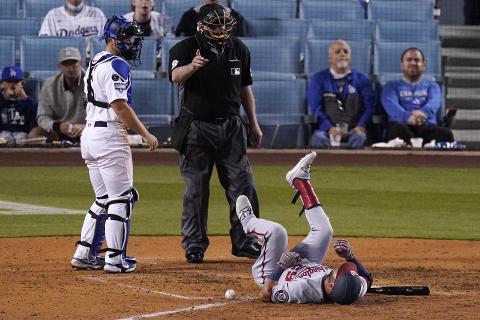 Washington Nationals' Yadiel Hernandez, right, lays on the ground after being hit by a pitch as Los Angeles Dodgers catcher Will Smith, left, watches and home plate umpire Brian Gorman gestures during the sixth inning of a baseball game Saturday, April 10, 2021, in Los Angeles. (AP Photo/Mark J. Terrill)