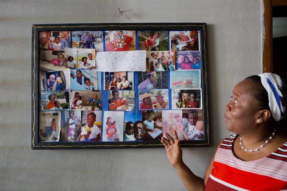 Nest of Hope orphanage Director Dallye Telemaque Bernard, points to pictures of children adopted from the orphanage in Port-au-Prince, Haiti on Thursday, June 28, 2018. She oversees the care of about 50 children, ranging in ages from 5 months to 13 years. Some are brought in by government social workers, or by police who find them in the streets. But most are dropped off by their impoverished parents. (AP Photo/Dieu Nalio Chery)