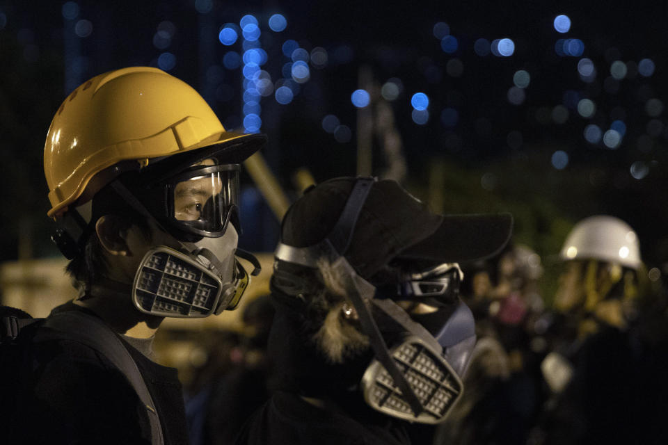 Protesters don gas masks and helmets as they defend a bridge leading into Chinese University of Hong Kong, in Hong Kong, early Thursday, Nov. 14, 2019. Protesters in Hong Kong battled police on multiple fronts on Tuesday, from major disruptions during the morning rush hour to a late-night standoff at a prominent university, as the 5-month-old anti-government movement takes an increasingly violent turn. (AP Photo/Ng Han Guan)