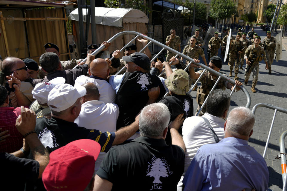 Soldiers scuffle with retired army members as they try to enter to the parliament building while the legislature was in session discussing the 2022 budget, during a protest in downtown Beirut, Lebanon, Monday, Sept. 26, 2022. The protesters demanded an increase in their monthly retirement pay, decimated during the economic meltdown. (AP Photo/Bilal Hussein)