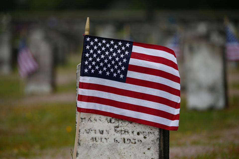 An American flag wraps itself around the gravestone of a veteran buried at Pine Grove Cemetery in New Bedford.