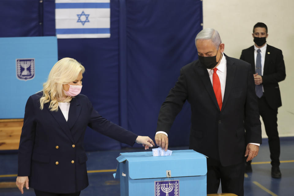 Israeli Prime Minister Benjamin Netanyahu and his wife Sara cast their ballots at a polling station as Israelis vote in a general election, in Jerusalem , Tuesday, March 23, 2021. Israelis began voting on Tuesday in the country's fourth parliamentary election in two years — a highly charged referendum on the divisive rule of Netanyahu. (Ronen Zvulun/Pool via AP)