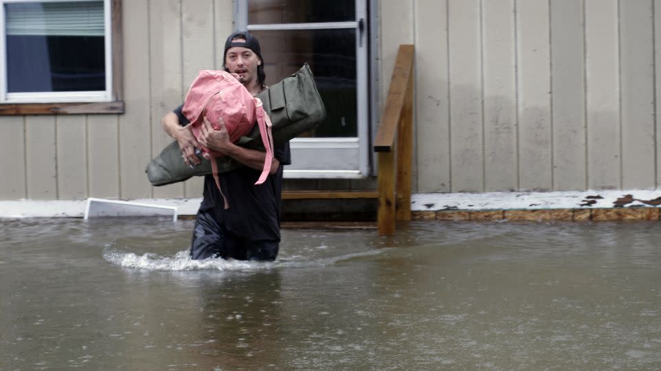 A man carries belongings through floodwaters from a home in Bridgewater, Vermont, on Monday.  - Hasan Jamali/AP
