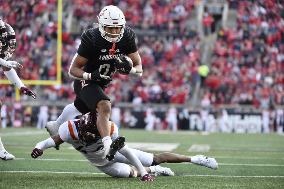 Louisville running back Isaac Guerendo (23) jumps over the tackle attempt by Virginia Tech cornerback Dorian Strong (44) during the second half of an NCAA college football game in Louisville, Ky., Saturday, Nov. 4, 2023. Louisville won 34-3. (AP Photo/Timothy D. Easley)