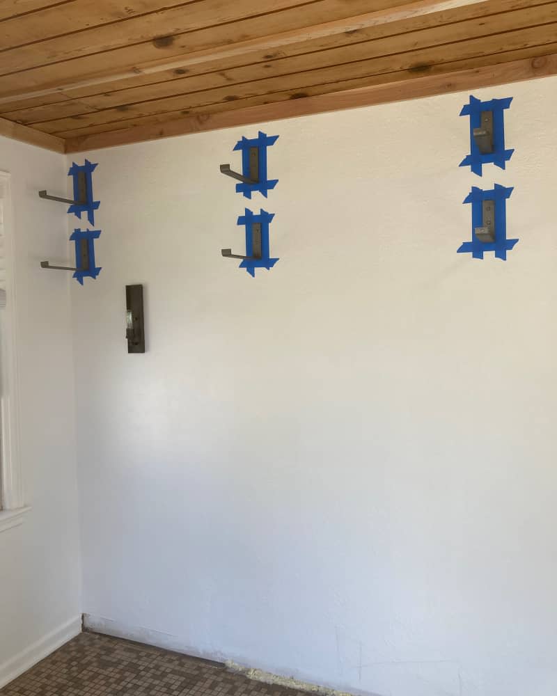 Shelf brackets hung at top of white room with wood ceiling.