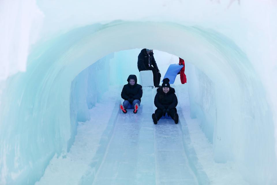 Visitors take a ride on an icy slide on opening day of the Lake George Ice Castles in Charles Wood Park in the village of Lake George Jan. 23, 2022. The castles include LED-lit sculptures, frozen thrones, ice-carved tunnels, caverns, slides, and fountains. The Ice Castles, which were all built by hand, will remain open through late February or early March, depending on the weather.