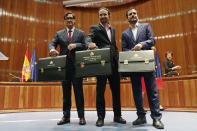Podemos (United We Can) leader Pablo Iglesias, centre, flanked by new Health Minister Salvador Illa, left and Podemos member Alberto Garzon, minister of consumption pose with their ministerial briefcases in Madrid, Spain, Monday, Jan. 13, 2020. Iglesias will be one of four deputy prime ministers and in charge of social rights and sustainable development after a total of 22 ministers took their oaths in Spain's center to far left-wing coalition administration, a first in a country once dominated by two main parties taking turns in power. (AP Photo/Manu Fernandez)