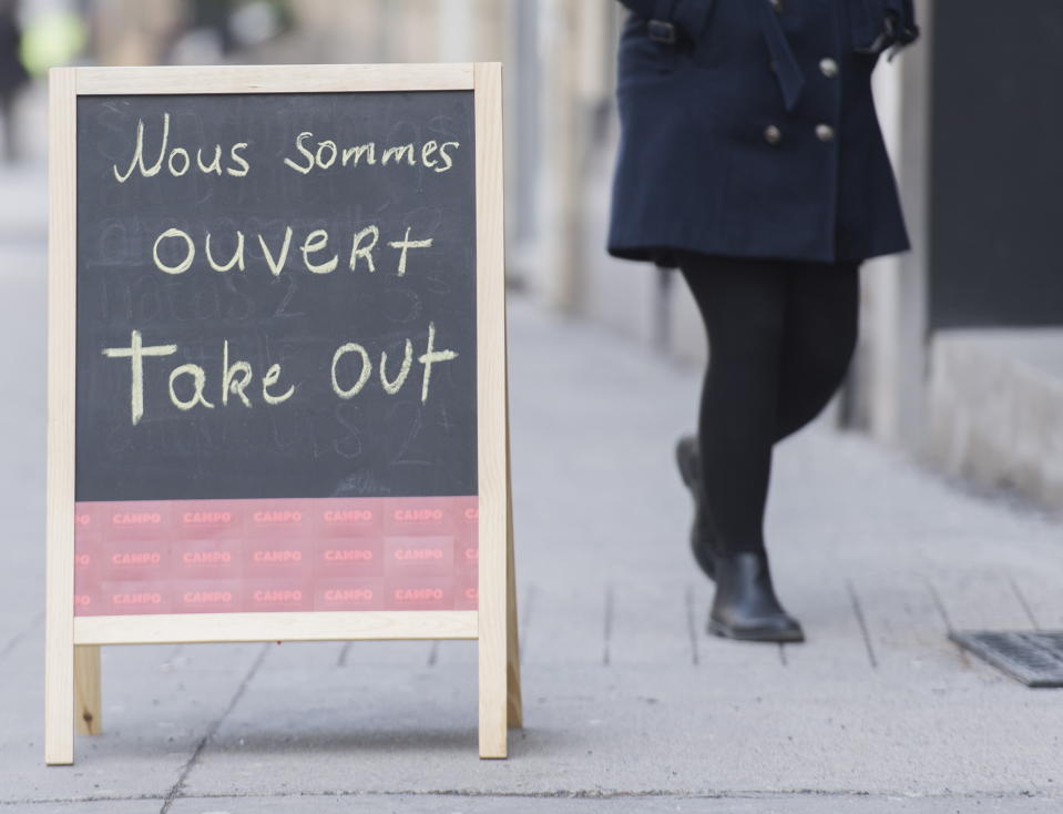 A woman walks into a restaurant offering 'take out' options in Montreal, Wednesday, March 18, 2020, as COVID-19 cases rise in Canada and around the world. For most people, the new coronavirus causes only mild or moderate symptoms. For some it can cause more severe illness. (Graham Hughes/The Canadian Press via AP)