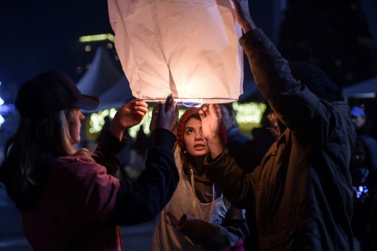 Young Kosovars light a lantern in front of the Kosovo national theater during a protest in support to Aleppo's population