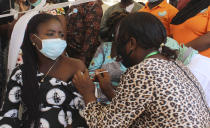 A Nigeria civil servant receives a dose of the AstraZeneca coronavirus vaccine, before she is allow access to her office in Abuja, Nigeria , Wednesday, Dec. 1, 2021. Nigeria has detected its first case of the omicron coronavirus variant in a sample it collected in October, weeks before South Africa alerted the world about the variant last week, the country's national public health institute said Wednesday. (AP Photo/Gbemiga Olamikan)