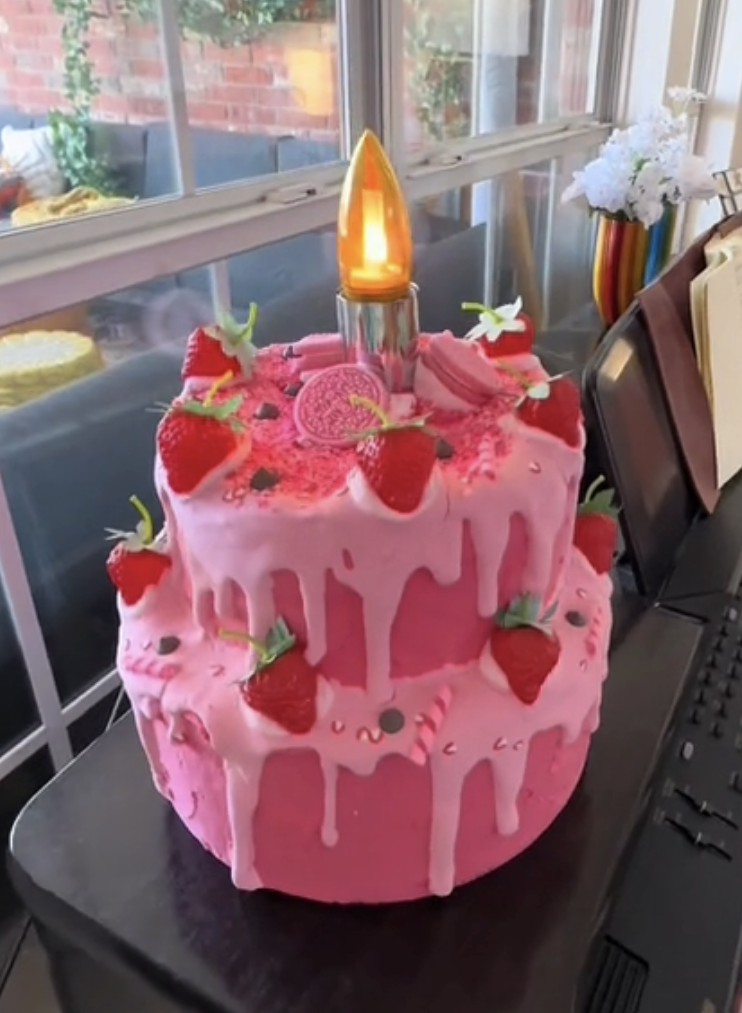 A decorative strawberry cake lamp with a single lit candle