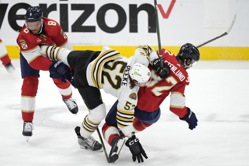 Boston Bruins defenseman Andrew Peeke (52) collides with Florida Panthers center Kevin Stenlund (82) and right wing Kyle Okposo (8) during the first period of Game 5 of the second-round series of the Stanley Cup Playoffs, Tuesday, May 14, 2024, in Sunrise, Fla. (AP Photo/Wilfredo Lee)