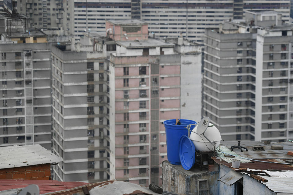 Un hombre limpia el interior de un contenedor de agua situado sobre el tejado de su casa en el vecindario de San Agustín, en Caracas, Venezuela, el 17 de mayo de 2020. La escasez de agua sigue agravándose en Venezuela en un momento en que la amenaza del coronavirus hace que lavarse las manos sea aún más crítico. (AP Foto/Matías Delacroix)