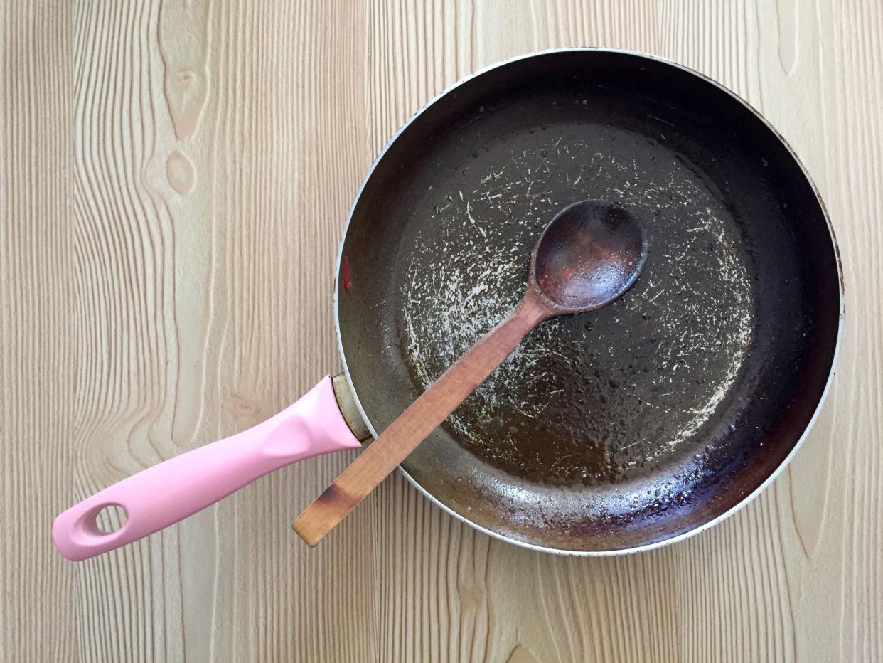 Directly above empty and dirty cooking pan with wooden spoon on the wood background