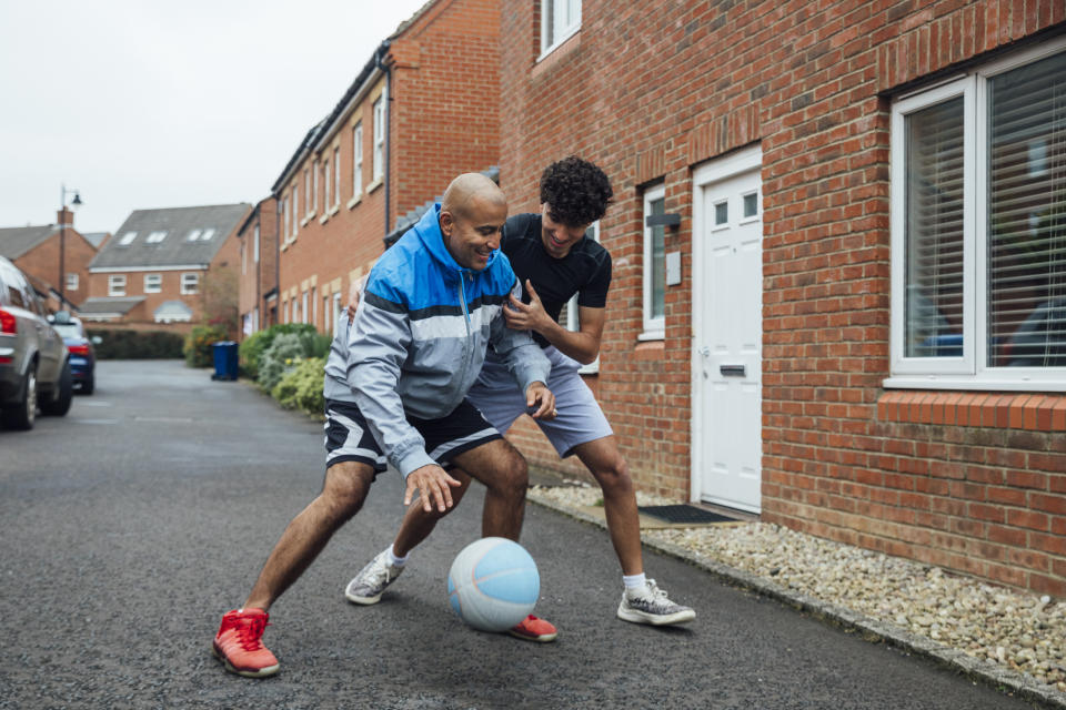 Father and son playing basketball together on a driveway