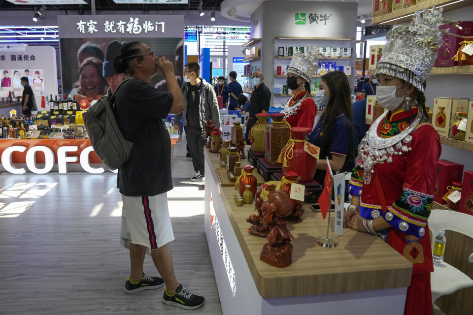 A man tries out a traditional Chinese wine as visitors tour a booth promoting Chinese food products at the China International Fair for Trade in Services (CIFTIS) in Beijing on Sept. 1, 2022. China's export growth weakened in August and imports shrank as high energy prices, inflation and anti-virus restrictions weighed on global and Chinese consumer demand. (AP Photo/Andy Wong)