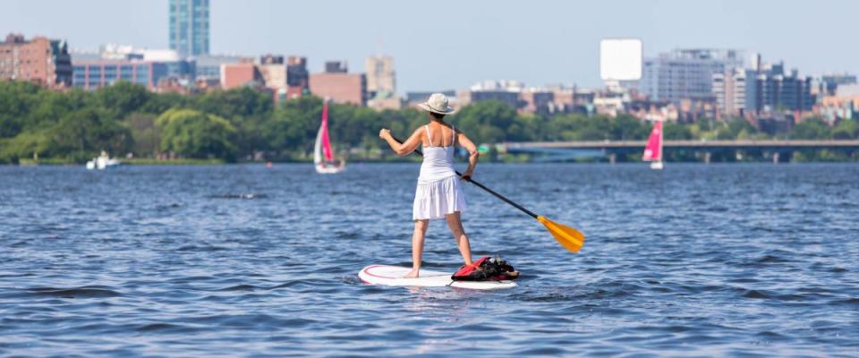 Old woman sailing on the Charles river on sunny day  with happy on Boston city background.