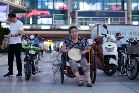 A 68-year-old woman with a stroke sits in a tricycle as she rests at a city square in Weifang