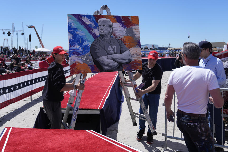 Artist Scott LoBaido, right, looks on as crew members move his painting of Republican presidential candidate former President Donald Trump before a campaign rally in Wildwood, N.J., Saturday, May 11, 2024. (AP Photo/Matt Rourke)
