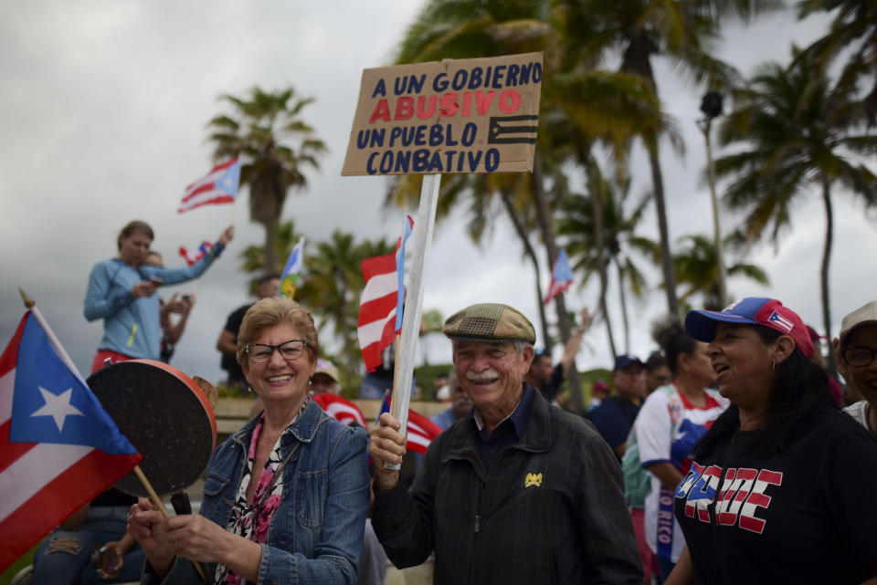 People join a protest organized by Puerto Rican singer Rene Perez of Calle 13 over emergency aid that until recently sat unused in a warehouse amid ongoing earthquakes, in San Juan, Puerto Rico, Thursday, Jan. 23, 2020. Protesters demanded the ouster of Gov. Wanda Vázquez. The sign reads in Spanish "For an abusive government, a combative people." (AP Photo/Carlos Giusti)