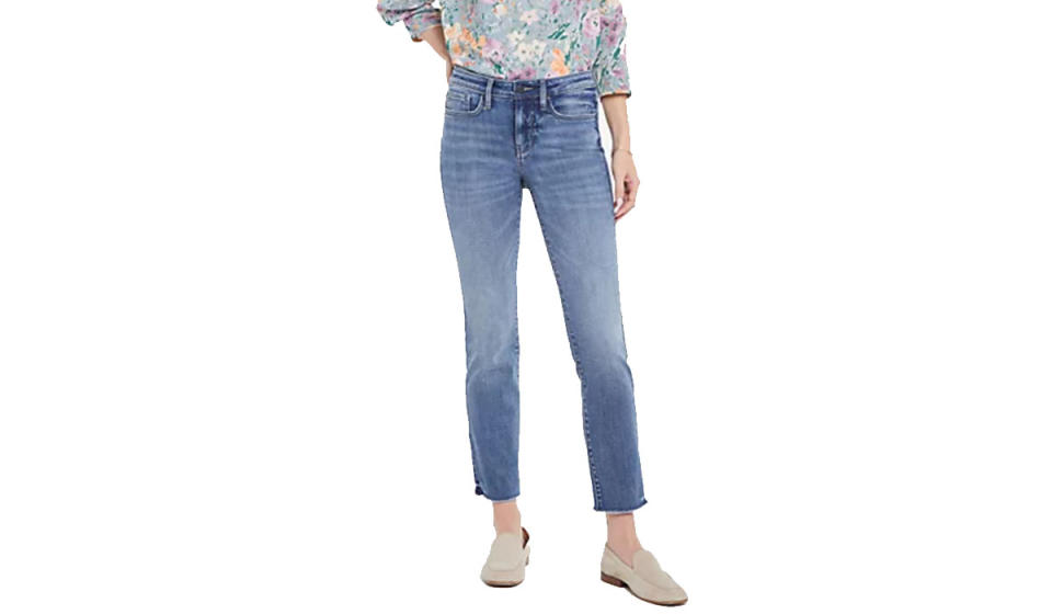 Woman wearing medium wash, ankle-length jeans, flat loafers, and a floral blouse. 