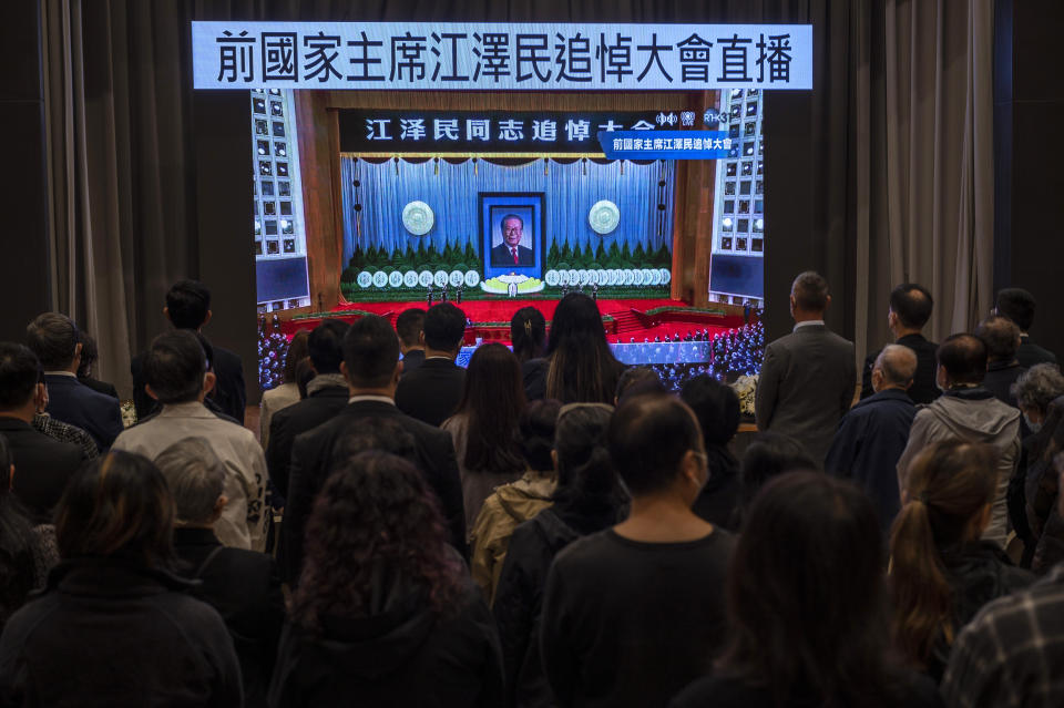Residents watch a live broadcast of the memorial service for late former Chinese President Jiang Zemin on a screen at a community center in Hong Kong, Tuesday, Dec. 6, 2022. A formal memorial service was held Tuesday at the Great Hall of the People, the seat of the ceremonial legislature in the center of Beijing. Words on screen read "Former Chairman Jiang Zemin memorial live broadcast." (AP Photo/Vernon Yuen)