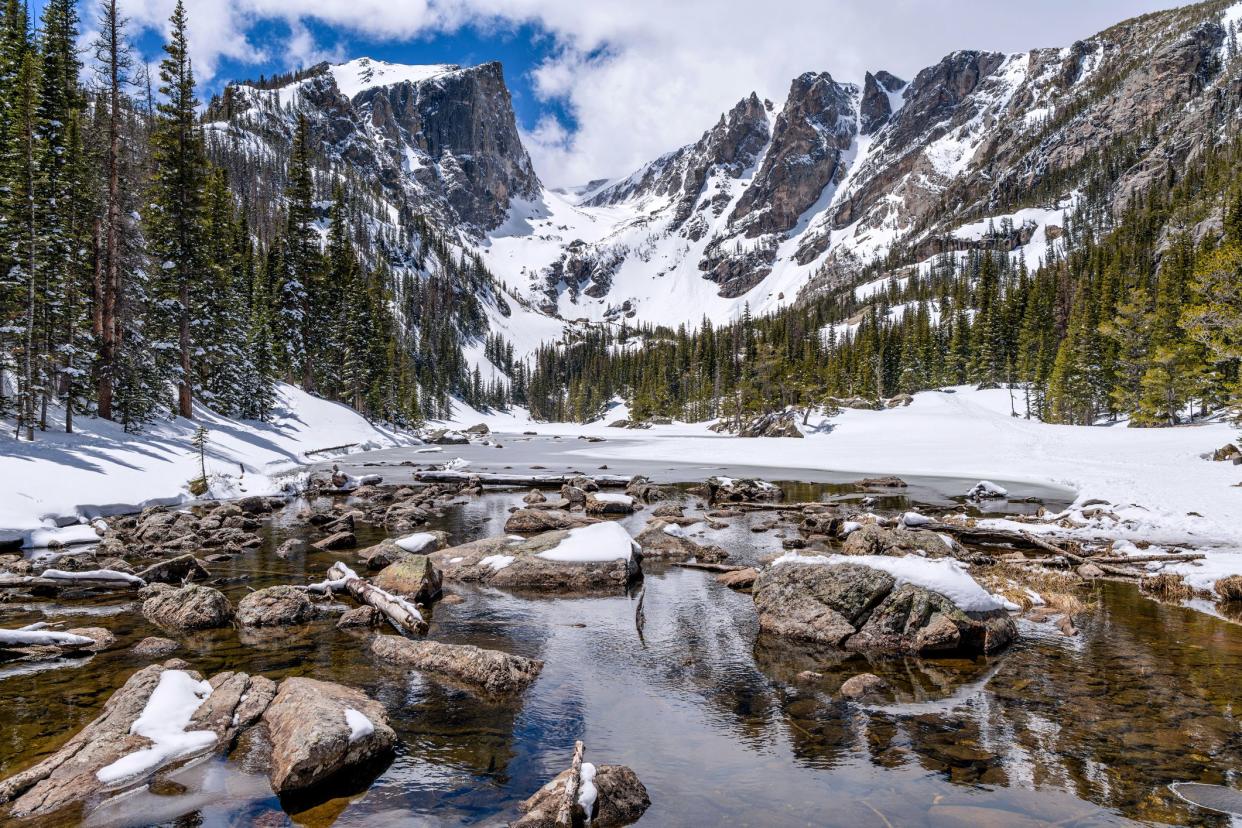 Dream Lake, mostly frozen, with Hallett Peak and Flattop Mountain in the background.