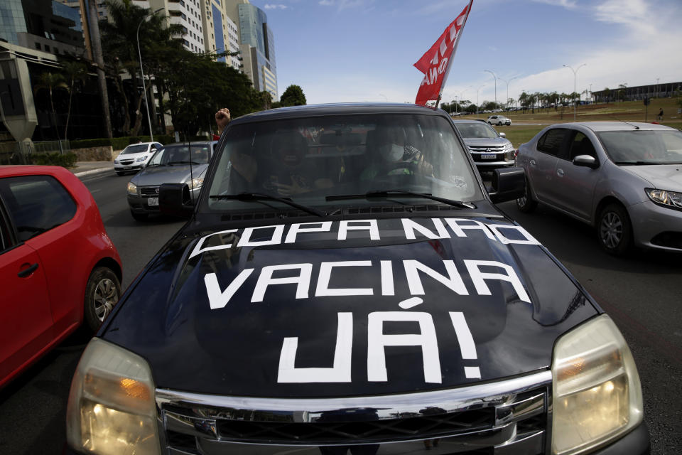 Protesters drive their car with a sign reading in Portuguese "Copa No, Vaccines Now" to protest the holding of Copa America in Brasilia, Brazil, Sunday, June 6, 2021. Brazil accepted hosting the South American soccer tournament after the original co-hosts were dropped: Colombia due to political protests and Argentina for rising of COVID-19 cases. (AP Photo/Eraldo Peres)