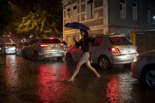 A woman crosses a street in Botafogo neighborhood in Rio de Janeiro, Brazil, as a downpour floods several areas of the city on April 8, 2019