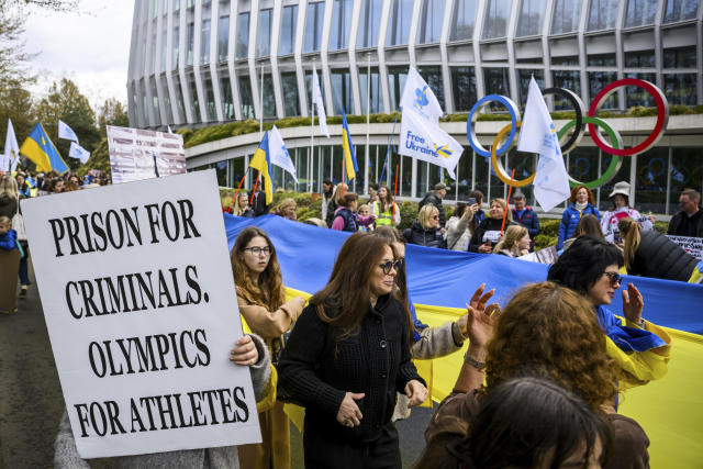Members of the Geneva branch of Ukrainian society in Switzerland protest during a rally to urge International Olympic Committee to reconsider their decision of participation of Russian and Belarusian athletes under white neutral flag at the next 2024 Paris Olympic Games, in front of the IOC headquarters, in Lausanne, Switzerland, Saturday, March 25, 2023. (Jean-Christophe Bott/Keystone via AP)