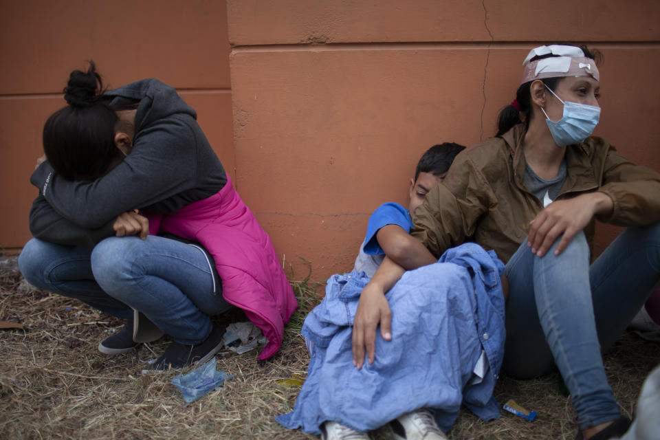 Injured women, part of a Honduran migrant caravan in their bid to reach the U.S. border, weep as they sit on the side of a highway after clashing with Guatemalan police and soldiers in Vado Hondo, Guatemala, Guatemala, Sunday, Jan. 17, 2021. (AP Photo/Sandra Sebastian)