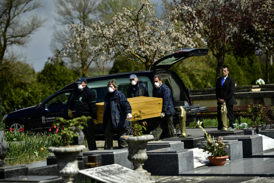 Undertakers wearing protection masks to protect from the coronavirus, carry a coffin to a burial at Salvador cemetery during the coronavirus outbreak, near to Vitoria, northern Spain, Monday, March 30, 2020. The new coronavirus causes mild or moderate symptoms for most people, but for some, especially older adults and people with existing health problems, it can cause more severe illness or death. (AP Photo/Alvaro Barrientos)