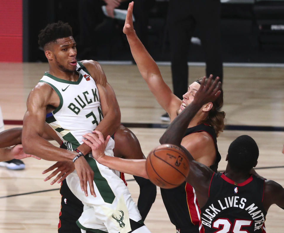 Milwaukee Bucks forward Giannis Antetokounmpo (34) passes the ball against Miami Heat forward Kelly Olynyk (9) and guard Kendrick Nunn (25) during the second half of an NBA basketball game Thursday, Aug. 6, 2020, in Lake Buena Vista, Fla. (Kim Klement/Pool Photo via AP)