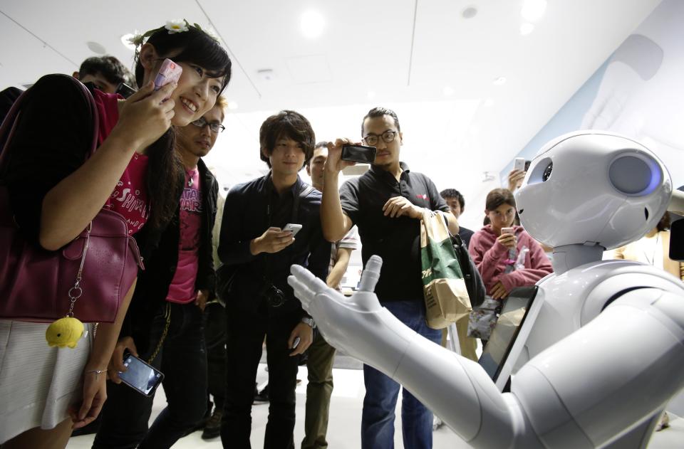 People look at SoftBank Corp's human-like robots named 'pepper' displayed at its branch in Tokyo