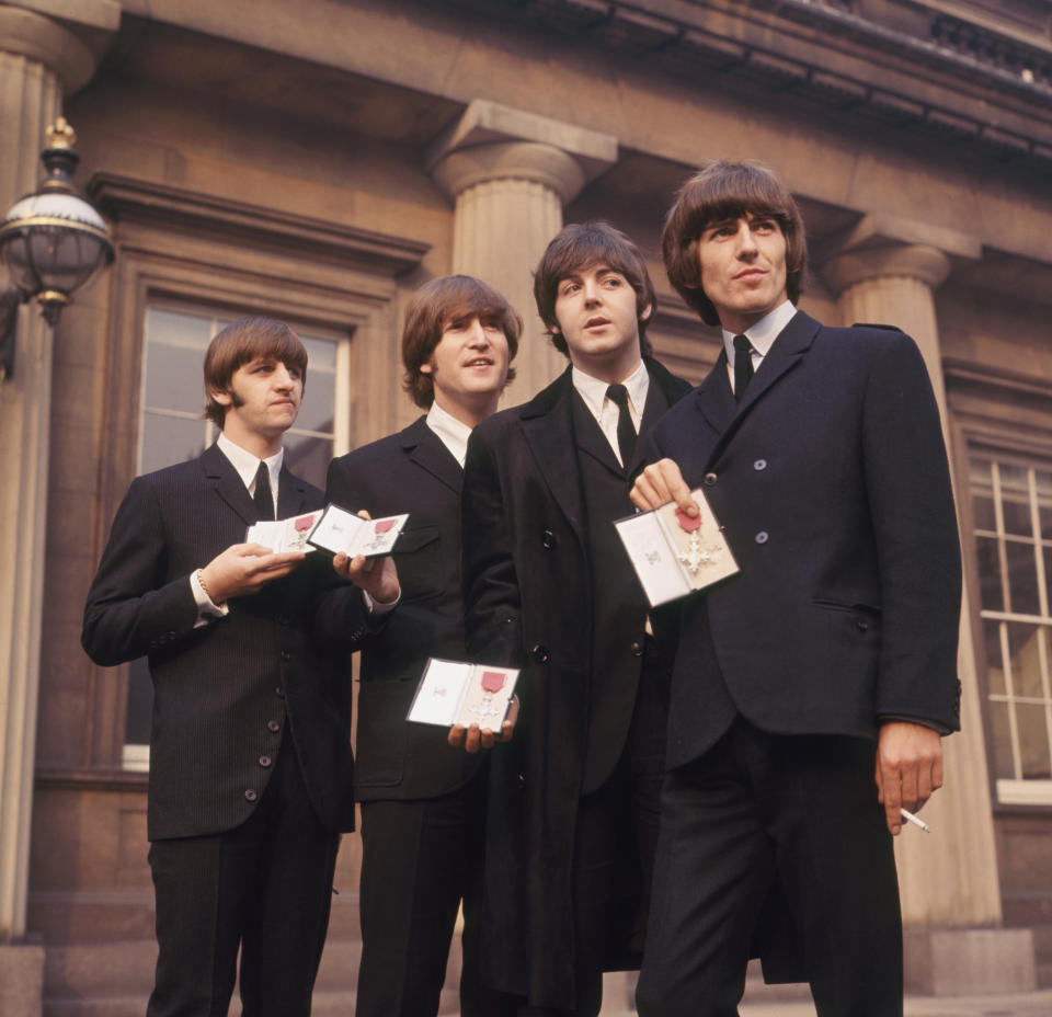 The Beatles showing their MBE Insignias in forecourt after receiving them from the Queen. L-R Ringo Starr, John Lennon, Paul McCartney and George Harrison.