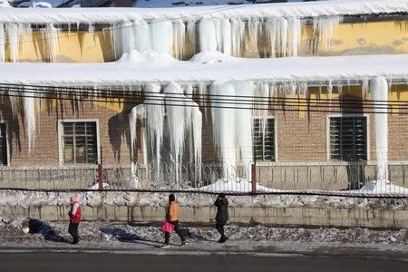 People look at icicles hanging on the roof of a factory building in Altay, Xinjiang Uighur Autonomous Region, China, January 12, 2016. REUTERS/Stringer