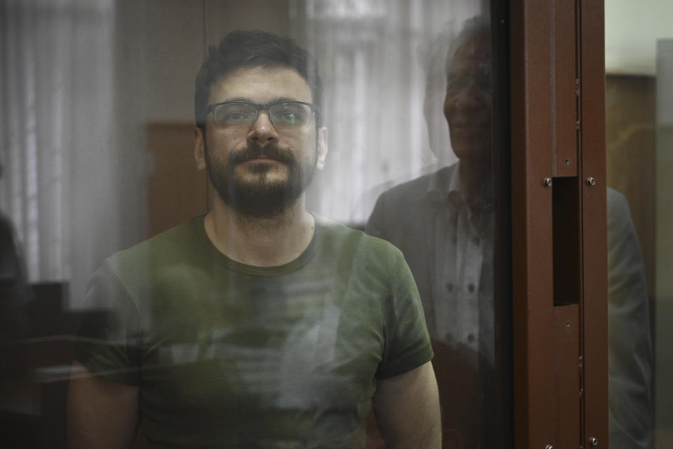 Russian opposition activist and a municipal deputy of the Krasnoselsky district Ilya Yashin stands in a cage at a court room during a hearing on his detention the Basmanny district court in Moscow, Russia, Wednesday, July 13, 2022. Yashin faces charges under a new law making it a crime to spread false information about the military that carry a potential sentence of up to 15 years in prison. (AP Photo/Dmitry Serebryakov)